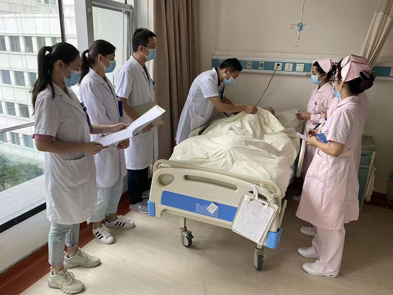 倪刚（左四）和医护人员在进行查房。受访者供图